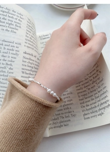 Detail of elegant S925 silver beaded bracelet with white pearls on a model's wrist
