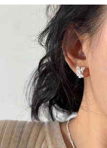 Detailed view of dainty S925 sterling silver butterfly stud earring on model's ear
