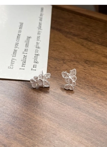 Detail of silver S925 butterfly stud earrings with delicate hollow filigree texture