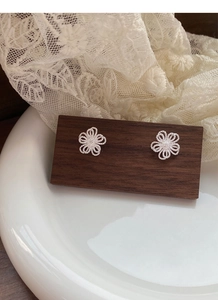 Macro de boucles d'oreilles fleurs évidées en argent avec texture mate sur support