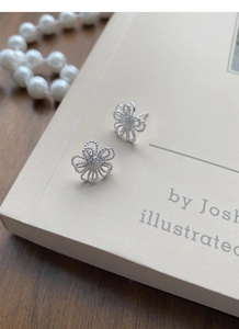 Vue détaillée de boucles d'oreilles fleurs en argent S925 sur une couverture de livre