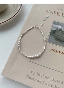 Macro detail of S925 sterling silver tag on a delicate pearl and faceted bead bracelet