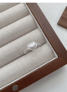 Detail of S925 silver heart ring with frosted texture and beaded band in a wooden box