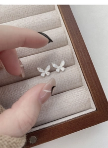Macro shot of silver butterfly studs with brushed texture in a velvet jewelry box