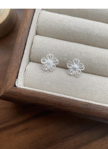 Gros plan sur les puces d'oreilles fleurs ajourées en argent S925 sur lin