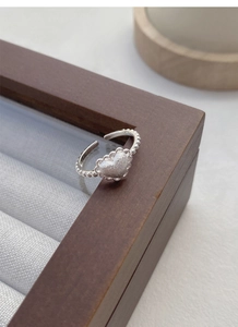 Detail of S925 silver heart ring with frosted finish on a dark wood jewelry box