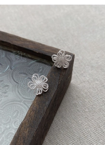 Gros plan de boucles d'oreilles fleurs ajourées en argent S925 avec bordure perlée fine
