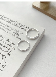 Macro d'anneaux minimalistes en argent mat posés sur une page de livre esthétique