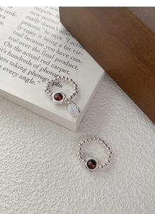 Macro detail of S925 silver beaded flower ring with garnet stone and Fu character tag