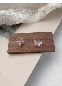 Detailed close-up of S925 sterling silver butterfly studs on wooden display stand