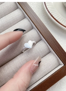 Macro shot of S925 sterling silver heart ring with matte brushed texture in a wooden box
