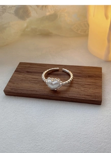 Macro shot of silver S925 heart ring with matte texture and beaded band on wood
