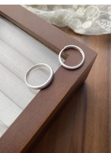 Détail de bagues en argent S999 mat sur présentoir en bois et dentelle blanche