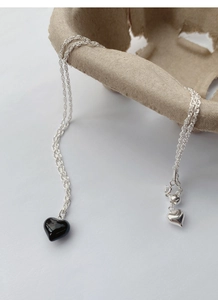 Detailed macro view of S925 silver necklace with black heart pendant and tassels