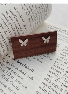 Detailed view of S925 sterling silver butterfly studs with brushed matte finish on wood