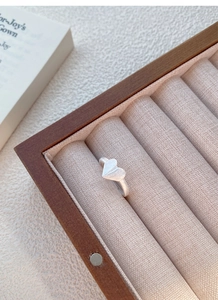Close-up of heart-shaped ring with brushed matte finish on a soft jewelry display