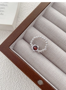 Detailed view of S925 silver beaded flower ring with deep red garnet stone in jewelry box
