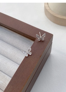 Detailed macro view of silver butterfly stud earrings with delicate brushed metal texture
