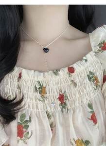Detail of S925 silver Y-shaped necklace featuring black heart pendant and tassels on neck