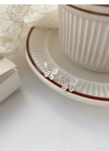 Macro detail of S925 sterling silver butterfly earrings with a brushed texture finish