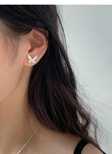 Close-up of minimalist S925 silver butterfly stud earring worn on a female ear