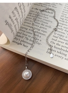Détail d'un collier en argent S925 avec perle et halo de diamants sur un livre