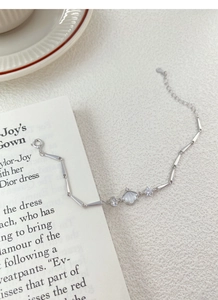 Close-up of S925 silver bamboo link bracelet featuring a white shell fan charm and zircon