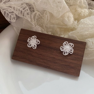 Boucles d'oreilles fleurs évidées en argent S925 sur un support en bois rustique