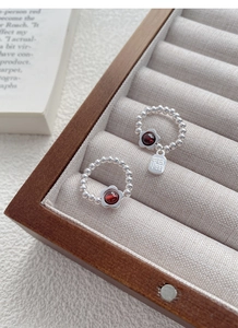 Macro shot of S925 silver beaded flower ring with red garnet and lucky charm pendant