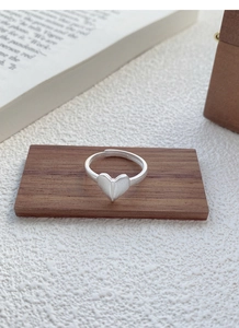 Macro shot of matte brushed S925 sterling silver origami heart ring on a wooden stand