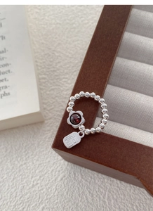 Macro detail of S925 silver beaded ring featuring a red garnet flower and Fu tag