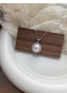 Détail du collier en argent S925 avec perle et halo de diamants sur bois brun
