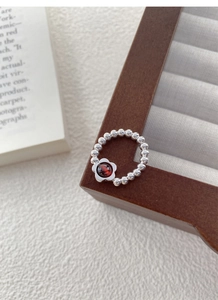 Macro shot of S925 sterling silver beaded ring with a garnet flower centerpiece on wood
