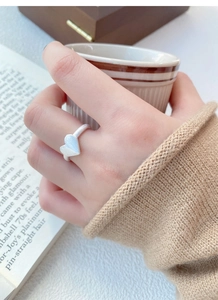 Macro shot of silver origami heart ring with brushed finish worn on hand