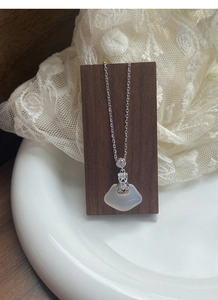 Vue macro d'un collier en argent avec pendentif éventail en calcédoine et pavé de diamants