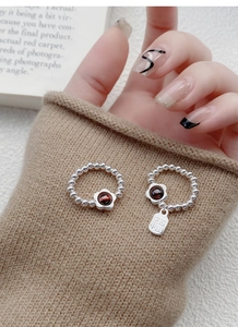 Macro shot of S925 silver beaded rings with red garnet flower and Fu character charm
