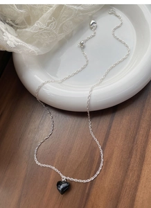 Detailed close-up of S925 silver necklace with black heart pendant and tassel details