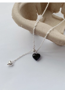 Detail of silver S925 necklace with black and silver heart pendants on a tray