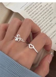 Close-up of S925 sterling silver bow and hollow heart rings on model's hand