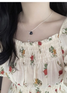 Detail of S925 silver necklace with black heart pendant worn on female neck