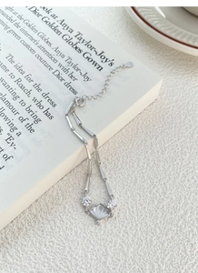 Detailed close-up of S925 silver bamboo-style bracelet with white shell pendant and zircons