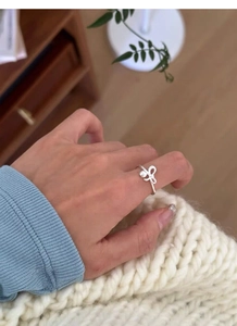 Detailed view of an S925 sterling silver bow ring with a white bead on a finger