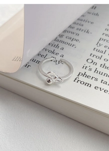 Macro detail of S925 silver bow ring with round bead on an open adjustable band