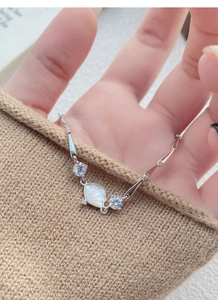 Macro detail of S925 silver bamboo bracelet with white shell fan charm and zircon stones