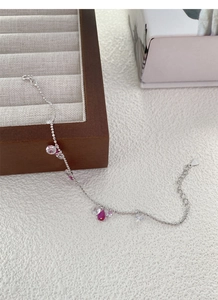 Gros plan d'un bracelet en argent S925 avec pierres roses en goutte et breloques en zircon
