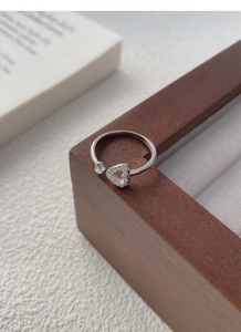Macro shot of silver S925 open ring with sparkling pavé-set heart details on wood