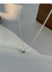 Macro shot of 925 sterling silver heart pendant with polished finish and bead chain detail