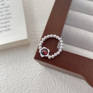 S925 sterling silver beaded ring featuring a red garnet flower on a vintage jewelry stand