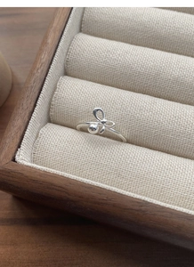 Macro shot of S925 sterling silver bow ring with round beads in a wooden jewelry box