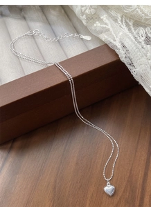 Detail of S925 sterling silver heart pendant necklace on wood and lace background